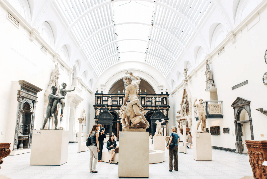 Museum sculpture gallery with visitors viewing classical artwork.