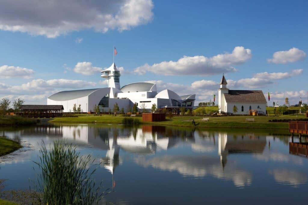 Discovery Park of America exterior with museum buildings reflected across the water.
